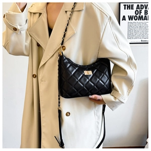Detail of black quilted shoulder bag with gold chain strap and metal turn-lock closure