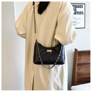 Detail of black quilted leather shoulder bag with gold chain strap and turn-lock