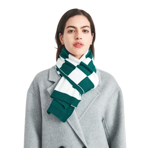 Green and white checkerboard knit scarf paired with a grey coat on a white background