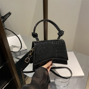 Chic black crocodile embossed trapezoid handbag with knotted handle and gold hardware