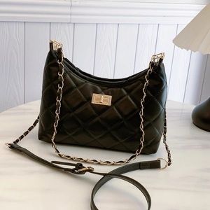Quilted black chain tote bag with gold hardware and dual straps on marble surface