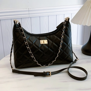 Chic black quilted chain shoulder bag with gold twist lock on white marble surface