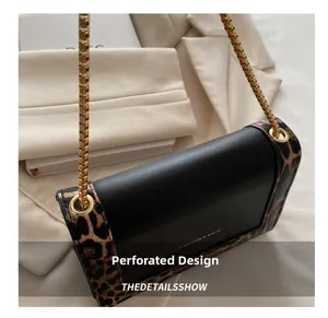 Detail of black leather and leopard print handbag with gold chain and metal eyelets