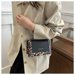 Detail of crossbody flap bag with leopard print texture and gold chain strap