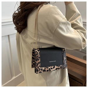 Detail of crossbody bag with black leather, leopard print trim and gold chain strap