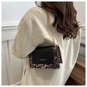 Detail of crossbody bag with leopard print side panels and golden chain strap for women