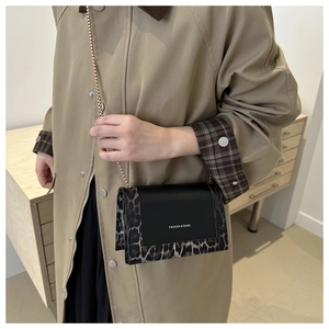 Detail of crossbody bag with leopard print side panels and golden chain strap on model