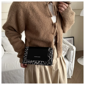Fashionable leopard print chain crossbody bag shown on model in a stylish indoor setting