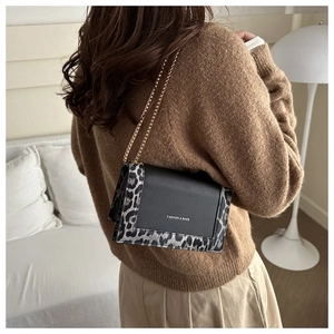 Detail of crossbody bag with leopard print accents and golden chain strap on model