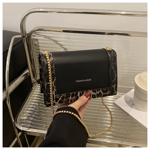 Detail of leopard print flap bag with gold chain strap on a modern display shelf
