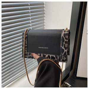 Detail of leopard print crossbody bag featuring a gold chain strap and fashion lettering
