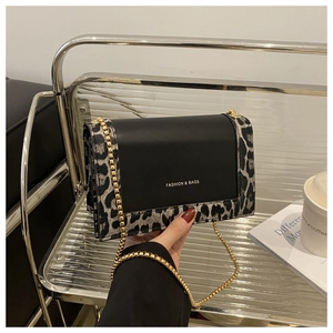 Close-up of leopard print shoulder bag with gold chain strap in an urban lifestyle setting