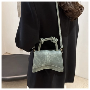 Detail of light blue hourglass handbag with knot handle worn by model in black blazer