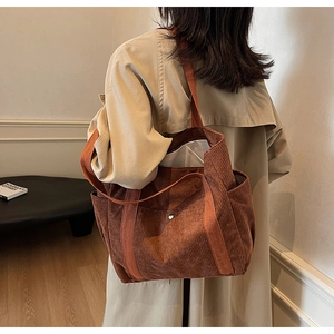 Detailed texture of brown corduroy tote bag showing the silver button and side pocket