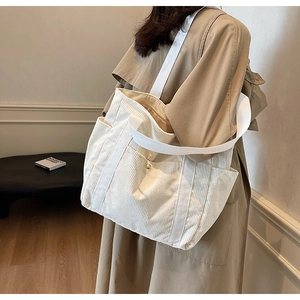 Detail of off-white corduroy tote bag with side pockets and durable woven shoulder straps