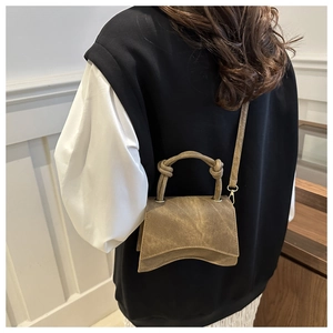 Detail of vintage brown curved handbag with knotted handle shown on shoulder