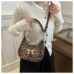 Détail du sac croissant léopard avec boucle nœud en métal argenté et bordure marron
