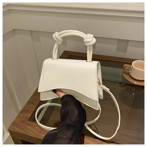 Detail of cream structured hourglass crossbody bag with knotted handle and gold hardware