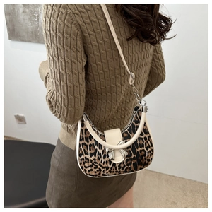 Détail du sac croissant à imprimé léopard avec boucle nœud sur un pull marron chic
