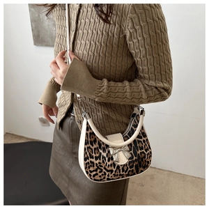 Sac bandoulière imprimé léopard avec nœud argenté et garniture en cuir blanc sur modèle