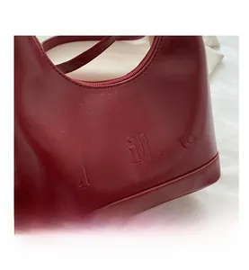 Detailed close-up of dark red crescent bag with embossed texture and zipper closure
