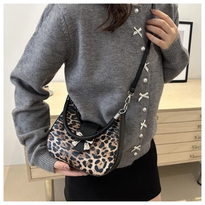 Détail du sac léopard avec nœud en métal argenté et finitions en cuir noir élégantes