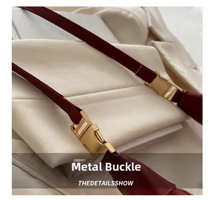 Close-up of premium gold hardware buckles on a burgundy leather dumpling bag strap