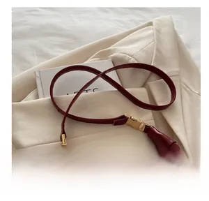 Detail of red crescent bag showing smooth lychee texture and shiny gold metal buckle