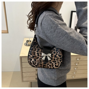 Détail du sac croissant léopard avec boucle papillon argentée et poignée en cuir noir