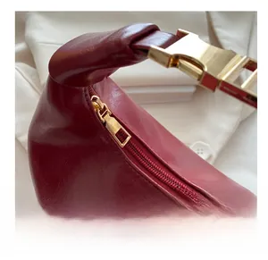 Detail of red leather shoulder bag showing smooth golden zipper and polished metal buckle