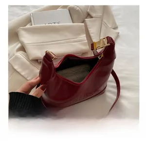 Detailed interior of a deep red semi-circular leather bag showing daily essentials