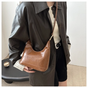 Detail of vintage brown leather shoulder bag with qaoihse embossed logo and silver buckles