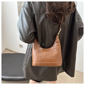 Detail of vintage brown crescent bag with embossed text on textured leather