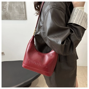 Detail of dark red leather hobo bag with embossed lettering and golden metallic buckle