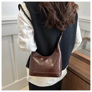 Close-up of chocolate brown leather dumpling bag with qaoihse embossed text details