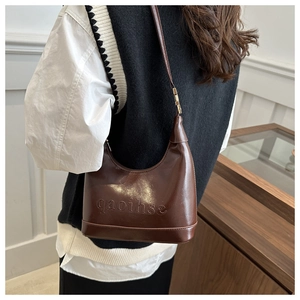 Detail shot of vintage brown hobo bag with embossed lettering and metal hardware