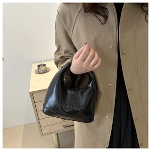 Close-up of black glossy leather crescent bag with embossed gaoihse letter detail