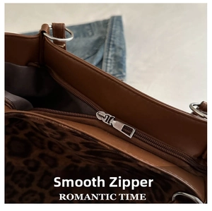 Detail of smooth silver zipper closure and leopard print lining on brown tote bag
