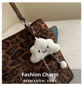 Plush white cloud charm with smile and striped ropes on leopard print tote bag
