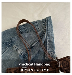 Detail shot of leopard print tote bag with slim brown handles on a casual denim background