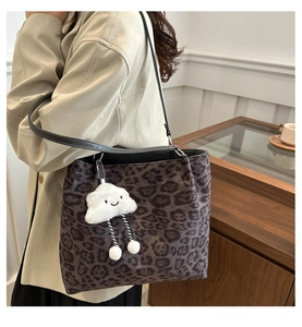 Detail of leopard print tote bag featuring a cute white cloud plush charm on the shoulder strap
