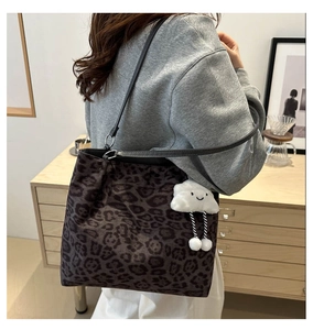 Macro detail of leopard print tote bag with a soft white plush cloud charm accessory