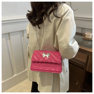 Detail of pink quilted leather bag with silver butterfly charm and fashion embossing