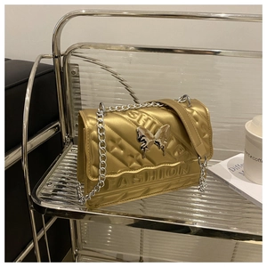 Detail of gold quilted bag with silver butterfly buckle and metallic chain strap