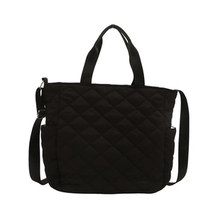 Grand sac cabas matelassé noir avec doubles poignées et bandoulière sur fond blanc