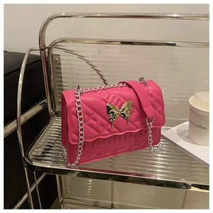 Detail of hot pink quilted crossbody bag featuring a golden butterfly clasp and chain strap