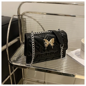 Detail of black quilted leather crossbody bag featuring a silver butterfly buckle and chain