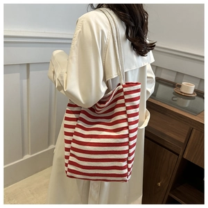 Detail of red striped canvas tote bag showing thick texture on a model's shoulder