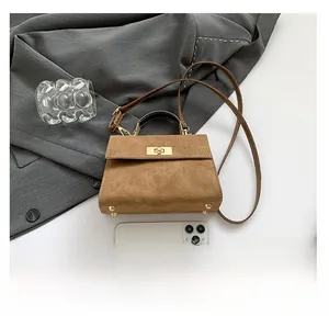 Size comparison of dark camel crossbody bag with smartphone and gold twist lock detail