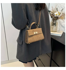 Close-up of brown suede crossbody bag with gold hardware on oversized blazer